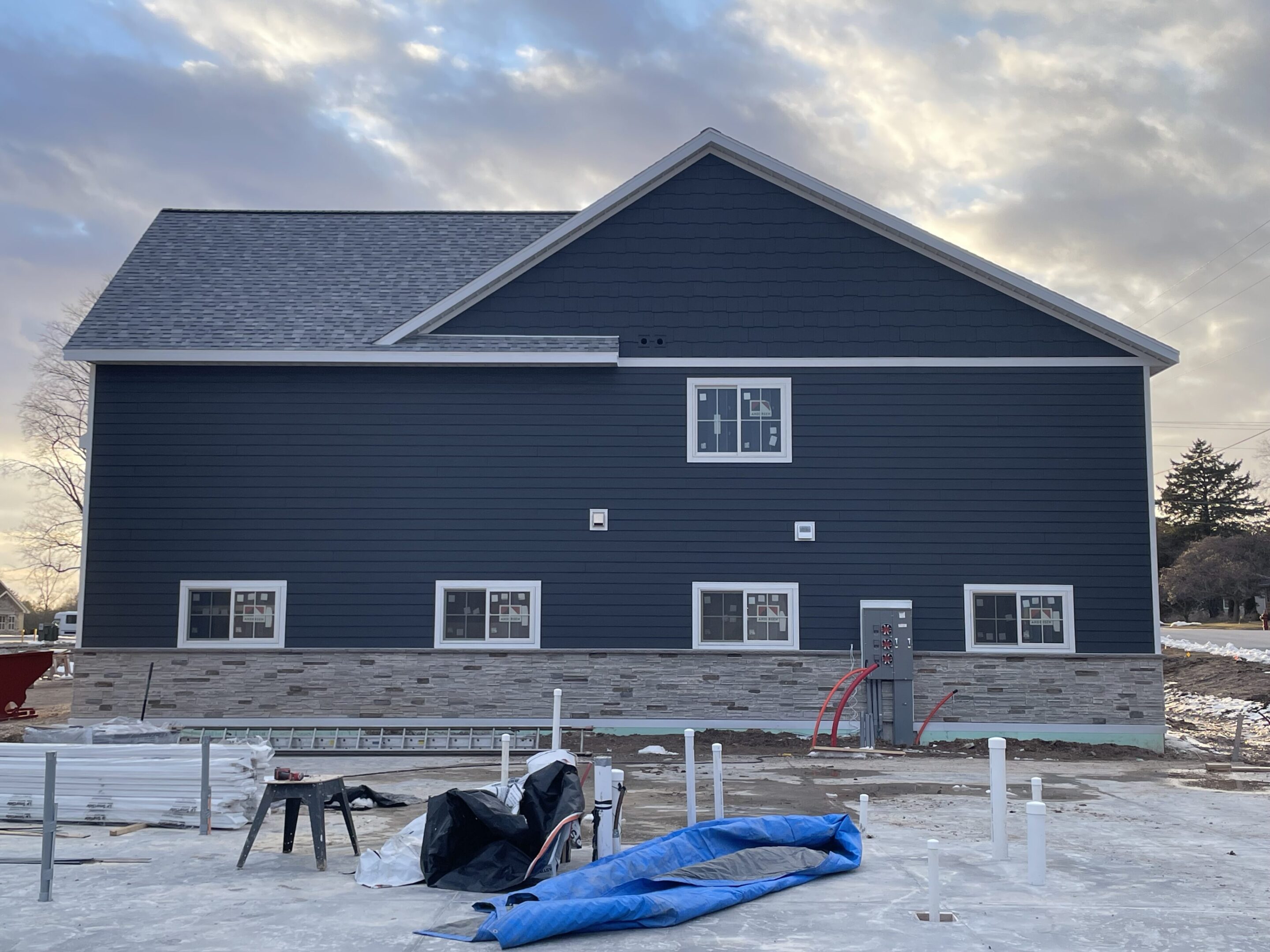 A dark blue house with stone accents under a cloudy sky.
